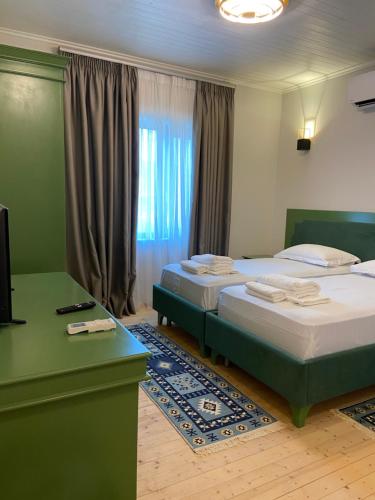 Këlcyrë“Sarajet” Bed&Breakfast的一间卧室设有两张床、一张桌子和一个窗口。