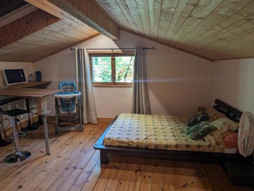 BlésignacGîte zen dans les bois的一间卧室配有一张床、一张书桌和一个窗户。