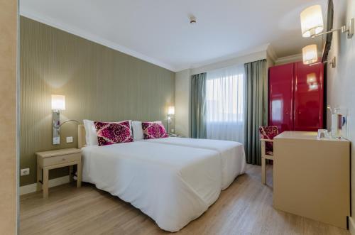 里斯本欧力斯普马克思德萨酒店的卧室配有带粉红色枕头的大型白色床