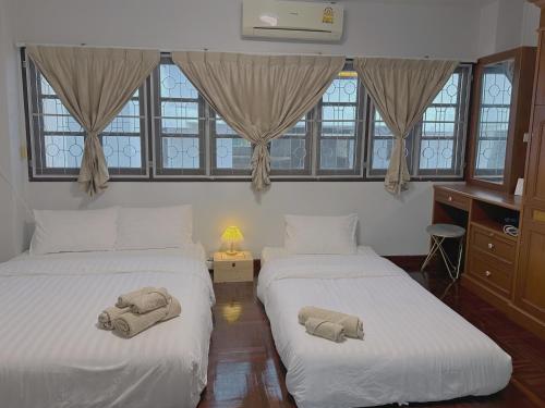 合艾Kong Khong Homestay的窗户间内的两张床和毛巾