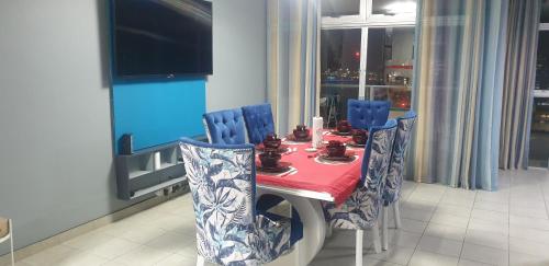 德班1403 on 10 South Beach的一张带蓝色椅子和红色桌布的餐桌