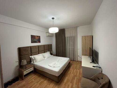 地拉那Rooms Dionis的一间卧室配有一张床、一台电视和一把椅子
