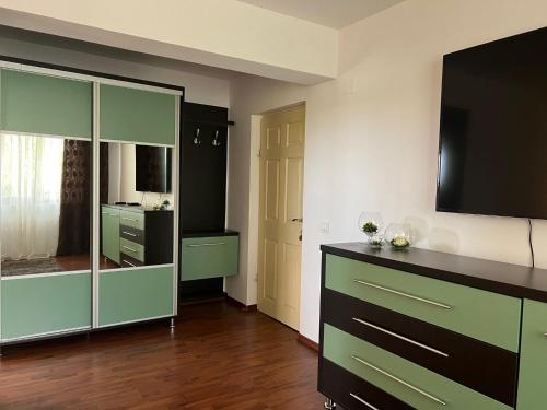 克里尚Vila CAMA的客厅配有绿色橱柜和平面电视。