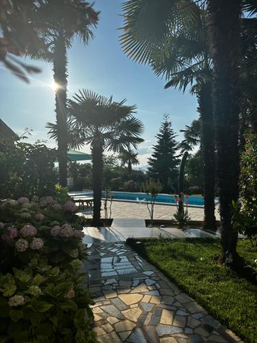 马林斯卡Holiday House Serenity的棕榈树和游泳池的石头步道
