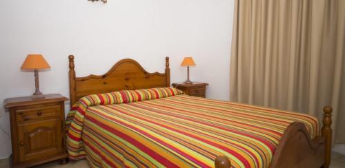 塔马达斯特Apartamento Bajo en el Tamaduste Zona Privilegiada的一间卧室配有一张带彩色条纹毯子的床