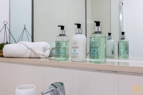 米尔顿凯恩斯Luxury 2-bed In central MK By Valore Property Services的一个带四瓶肥皂和毛巾的架子