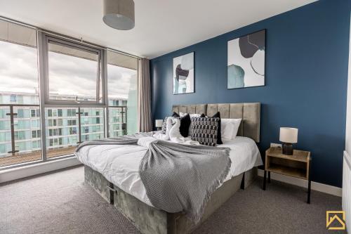 米尔顿凯恩斯Luxury 2-bed In central MK By Valore Property Services的一间卧室拥有蓝色的墙壁,配有一张带枕头的床。