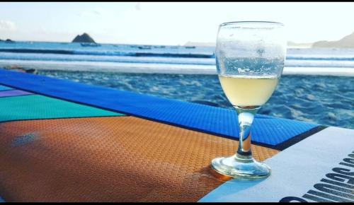 普拉亚Mahkota Atia Bungallow的坐在海边的桌子上喝一杯葡萄酒