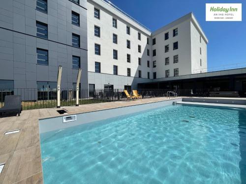 第戎Holiday Inn Dijon Sud - Longvic, an IHG Hotel的大楼前的大型游泳池