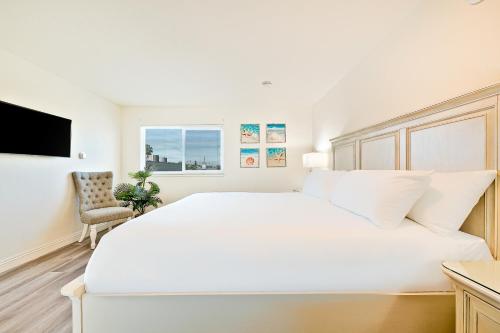 纽波特海滩Sunshine Fun Time的白色卧室配有一张白色的大床和一把椅子