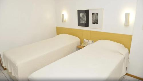 特雷西纳Rede Andrade Luxor的配有白色床单的酒店客房内的两张床
