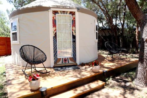 奥斯汀Camposanto Glamping - The Macaw Yurt的一座带两把椅子和门廊的小房子