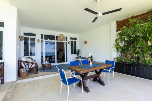白豪斯Ivy's Cove Beach Side Condo - Luxury Villa的庭院配有木桌和蓝色椅子