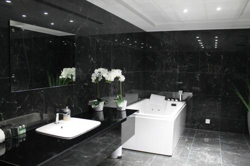 SkänningeSkänninge stadshotell的黑色瓷砖浴室设有两个盥洗盆和一个浴缸