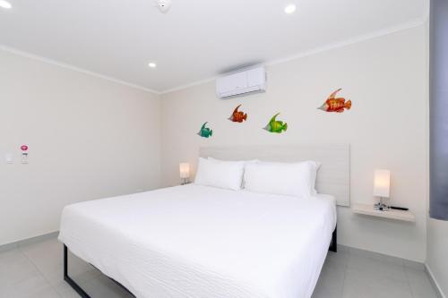 棕榈滩Summerside 4 Rooi Santo 10-A的白色卧室配有白色床,墙上挂着蝴蝶