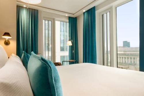 曼彻斯特Motel One Manchester-St. Peter´s Square的一间卧室配有一张带蓝色窗帘和窗户的床。