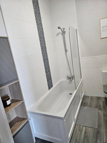 波特拉什Saltwater Edge Apartment的带淋浴的浴室配有白色浴缸。
