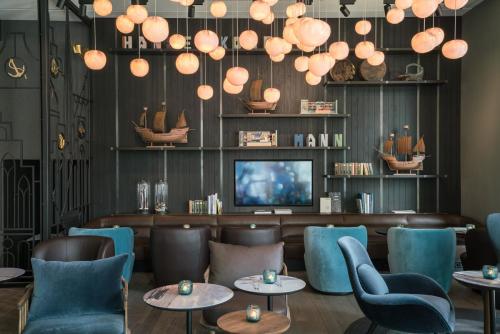 吕贝克Motel One Lübeck的餐厅设有蓝色的桌椅和电视。