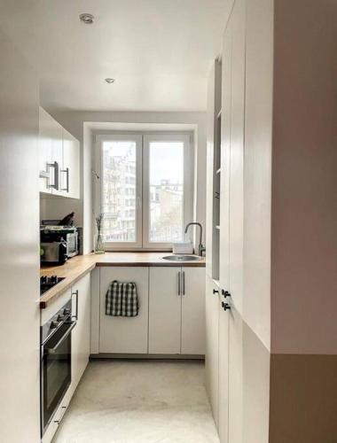 巴黎Charmant appartement parisien, spacieux & lumineux的白色的厨房设有水槽和窗户