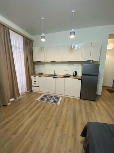 第比利斯Tbilisi cozy apartment的厨房配有白色橱柜和黑色冰箱。