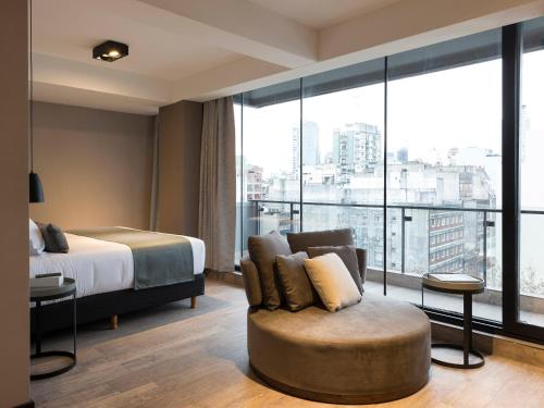 布宜诺斯艾利斯Casa Joseph的酒店客房设有一张床铺、一把椅子和一个大窗户。
