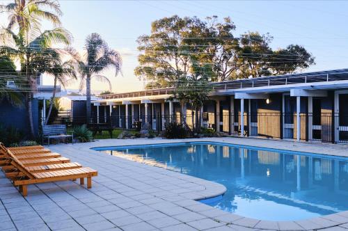 马拉库塔Mallacoota Hotel Motel的一座游泳池,旁边设有长凳