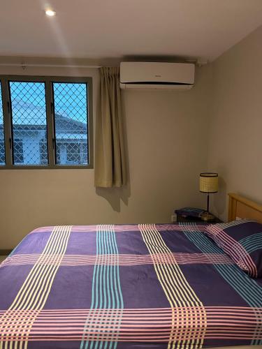 南迪Pacific FairPrice的一间卧室配有一张带紫色棉被的床和两个窗户。