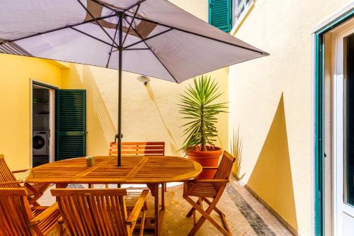 奥埃拉斯Jacuzzi, garden, pool & barbecue beach House, 15mn from Lisbon center的天井上配有带遮阳伞的木桌