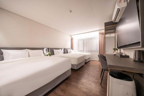 木浦市Cloud in Hotel Mokpo Peace Square的酒店客房配有两张床和一张书桌