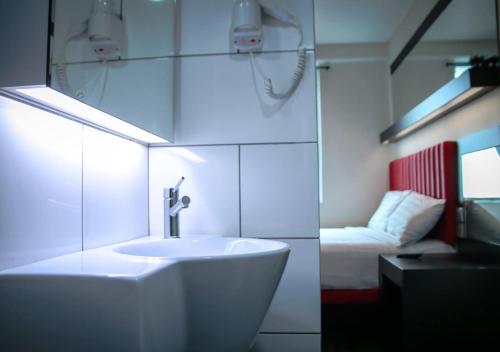 怡保Hotel Pi Ipoh的白色的浴室设有水槽和一张床