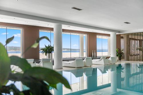 塞尔瑟Luxury Hotel Amabilis的一个带白色椅子的游泳池以及大海