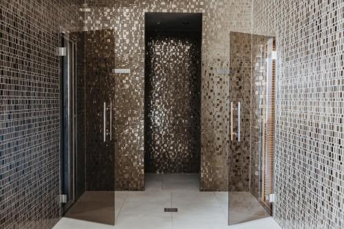 塞尔瑟Luxury Hotel Amabilis的浴室设有2个铺着棕色瓷砖的摊位。