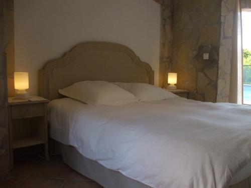 滨海卡涅塞尚别墅的一间卧室配有一张白色的床,桌子上配有两盏灯