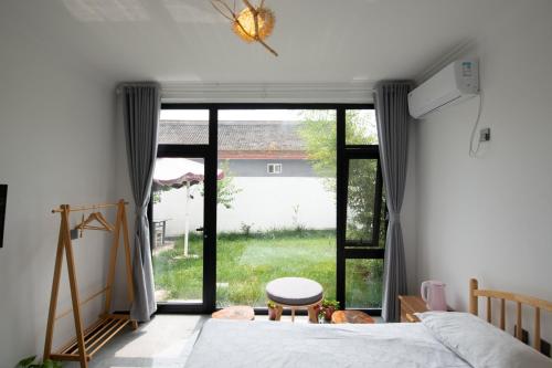 怀柔雁溪-棠棣民宿的一间卧室设有一张床和一个大窗户