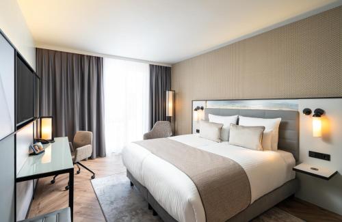 科隆Leonardo Royal Hotel Cologne Bonn Airport的酒店客房设有一张大床和一张书桌。