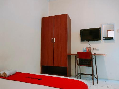 日惹RedDoorz near Kampus UNY Jogja的客房设有1张床、1张办公桌和1台电视。