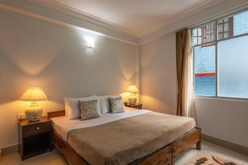 甘托克StayVista's Mystic Nest - Mountain & Valley-View Apartment with Contemporary Interiors & Modern Amenities的一间卧室配有一张带两盏灯的床和一扇窗户。
