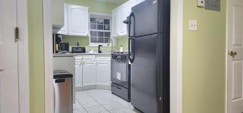 HillsideModern 2BR Apartment Jamaica Queens NYC的厨房配有黑冰箱和白色橱柜。