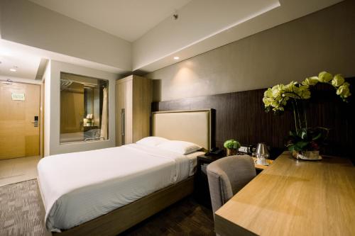 马尼拉Sotogrande Hotel Katipunan的一间卧室配有一张床、一张桌子和一张桌子