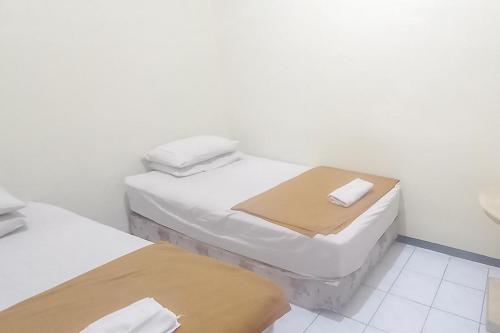 玛琅Hotel Malang near Alun Alun Malang RedPartner的白色墙壁客房中的两张单人床