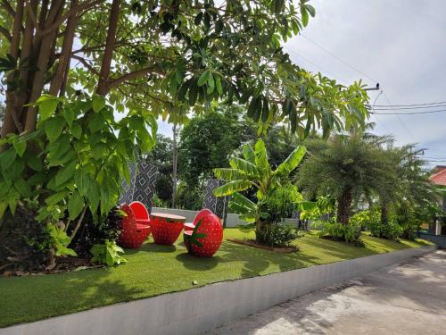 Ban Kut Ngongกานต์สินี อินน์ รีสอร์ท的草地上带三把红色椅子的花园