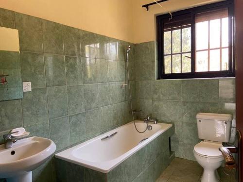 姆巴拉拉3-Bedroom Mbarara Apartment with Optional Farm Tour的带浴缸、卫生间和盥洗盆的浴室