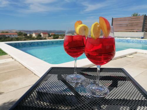 斯克拉丁Villa Scolopax rusticola Skradin with heated pool的两个酒杯坐在游泳池旁的桌子上