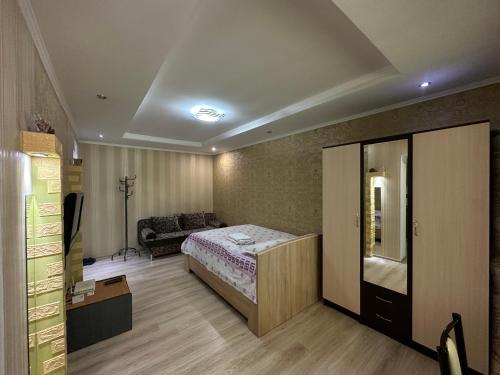 (( Turksib ))Однокомнатная квартира напротив Аэропорта Алматы的一间卧室配有一张床和一张沙发