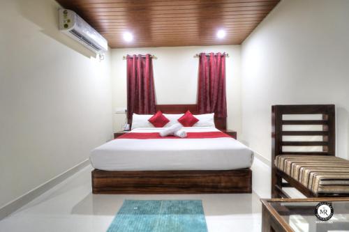 马迪凯里Coorg Avani Holiday Inn的一间卧室配有一张带红色窗帘的大床