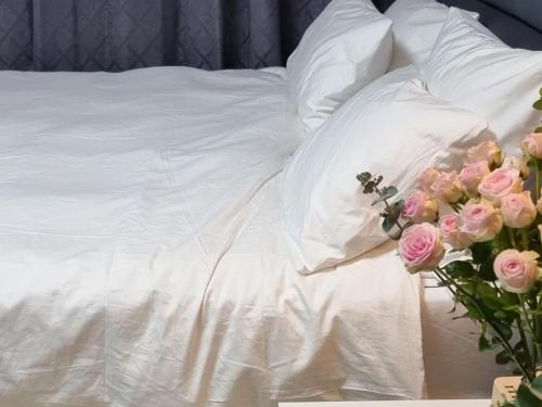 春川Cooing的一张床上铺有白色床单和粉红色玫瑰