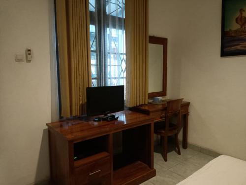 日惹RedDoorz at Griya Cemara Homestay Yogyakarta的客房设有一张带电视和镜子的书桌