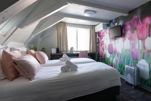 阿姆斯特丹马尔塔图里酒店的卧室配有一张大白色床,墙上挂着鲜花