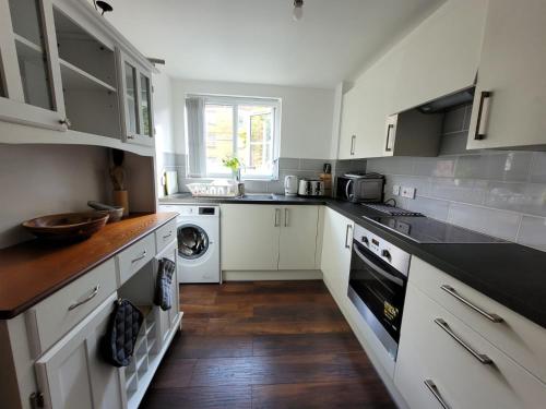 伦敦Comfortable Two Bedroom Modern Apartment的厨房配有白色橱柜、洗衣机和烘干机