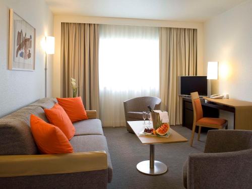 贝尔福贝尔福中心阿特丽亚诺富特酒店的一间客厅,客厅配有沙发和一张书桌,位于酒店的房间